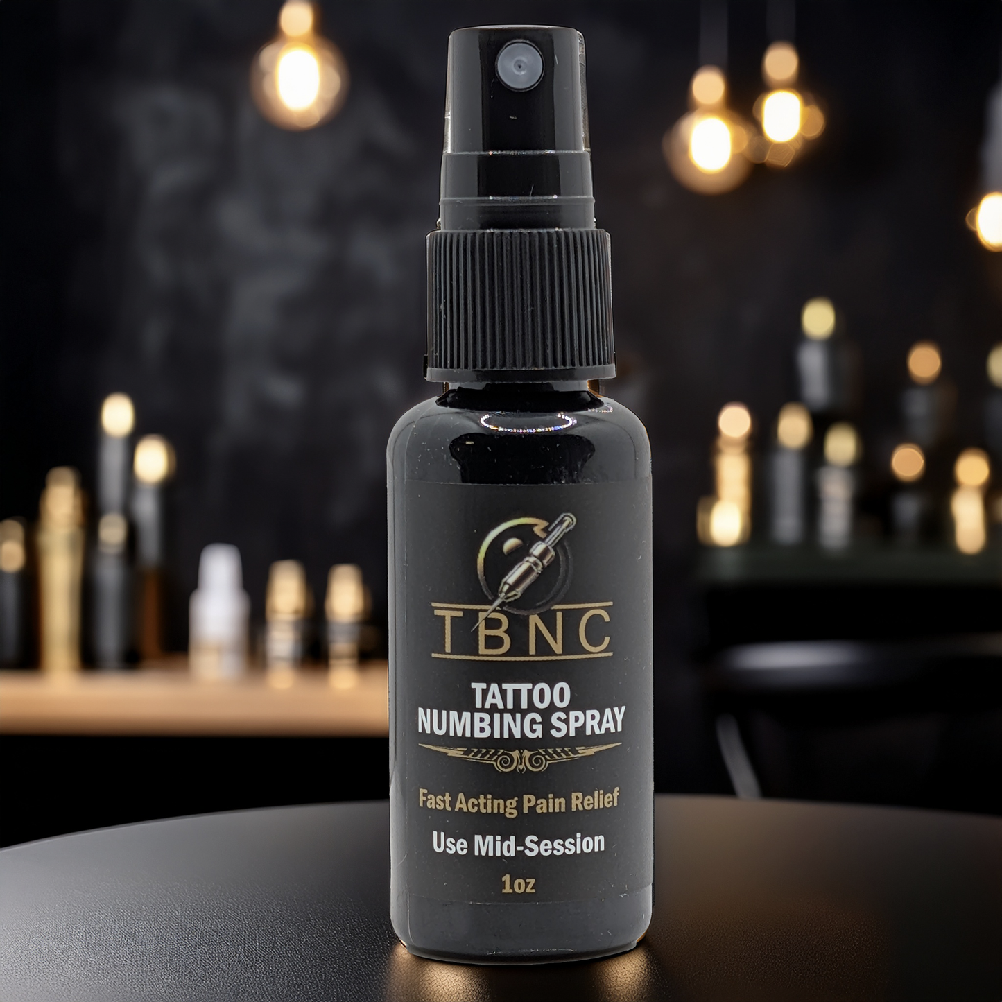 A black bottle labeled "Tattoo Numbing Spray - Mid Session" by TBNC - The Best Numbing Cream sits on a dark surface, providing fast pain relief; blurred lights and bottles fill the background.