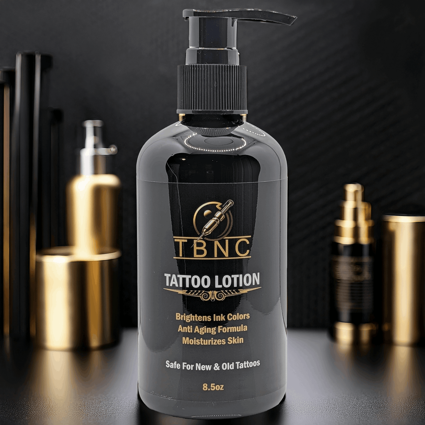 A black pump bottle of TBNC – The Best Numbing Cream Tattoo Lotion - Peppermint sits on a reflective surface among gold and black bottles, with a label that highlights moisturizing skin and enhancing tattoo vibrancy and brightness.
