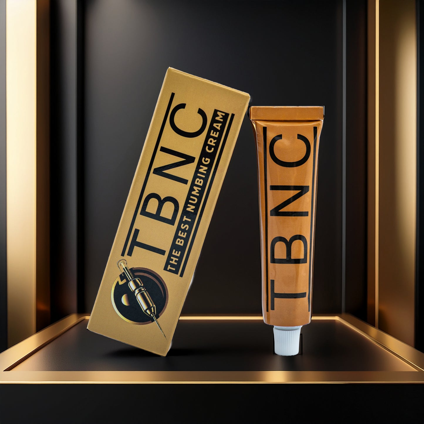A gold and black box labeled "Tattoo Numbing Cream XL" by TBNC - The Best Numbing Cream sits beside a matching gold tube with "TBNC" printed vertically, both on a sleek shelf—trusted by tattoo artists for maximum comfort.