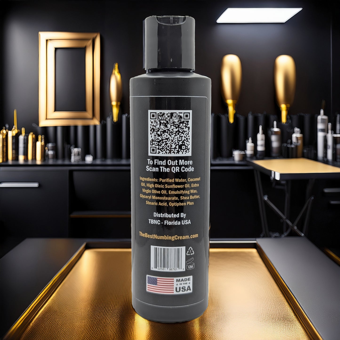 A black bottle of TBNC - The Best Numbing Cream Tattoo Aftercare Lotion - Unscented, featuring a QR code and ingredient list, stands on a gold surface in a sleek black and gold room with art, vases, tattoo gear, and a "Made in USA" flag label.