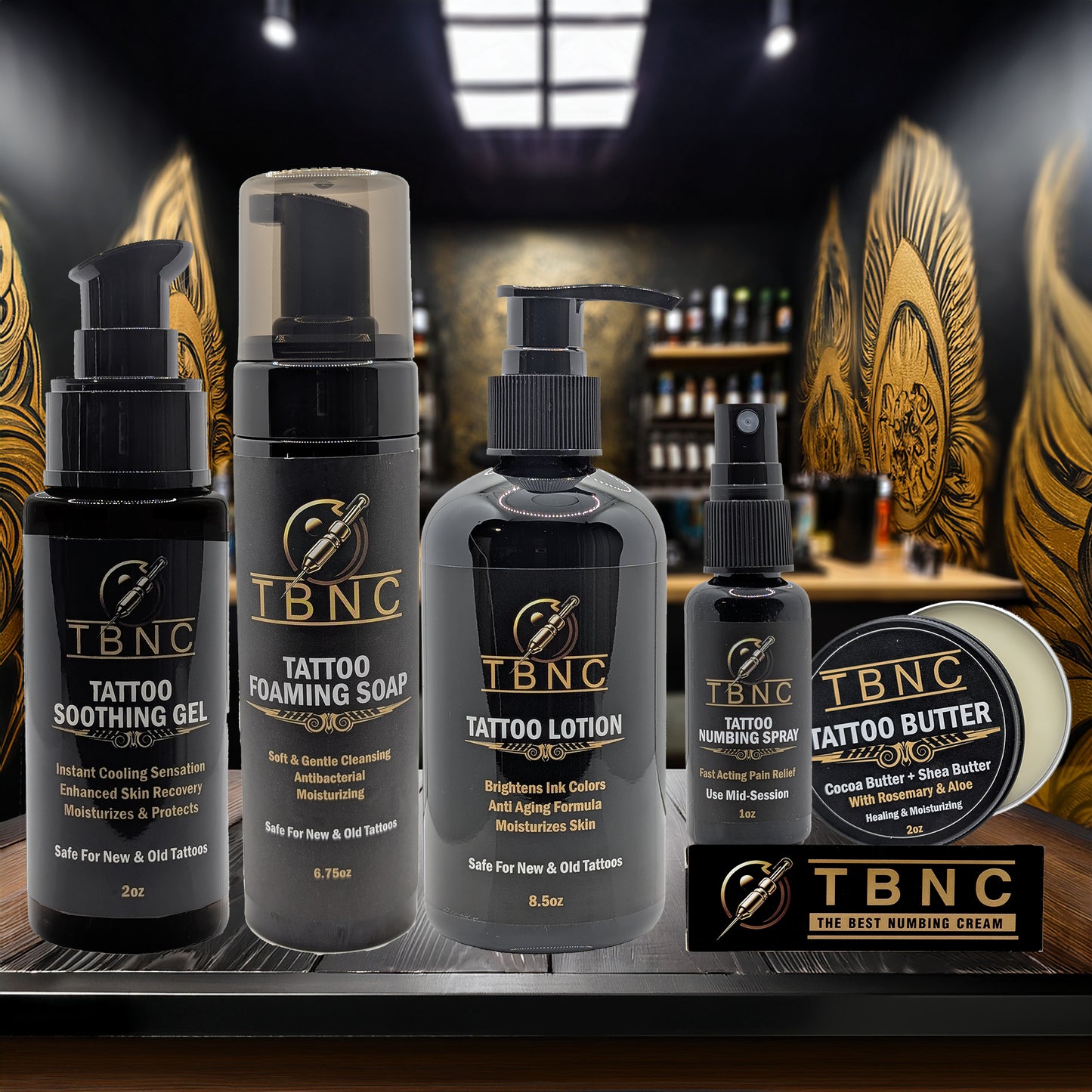 A display of TBNC - The Best Numbing Cream’s Tattoo Numbing & Aftercare Bundle is arranged on a counter with a tattoo studio background, showcasing products designed for optimal tattoo healing.