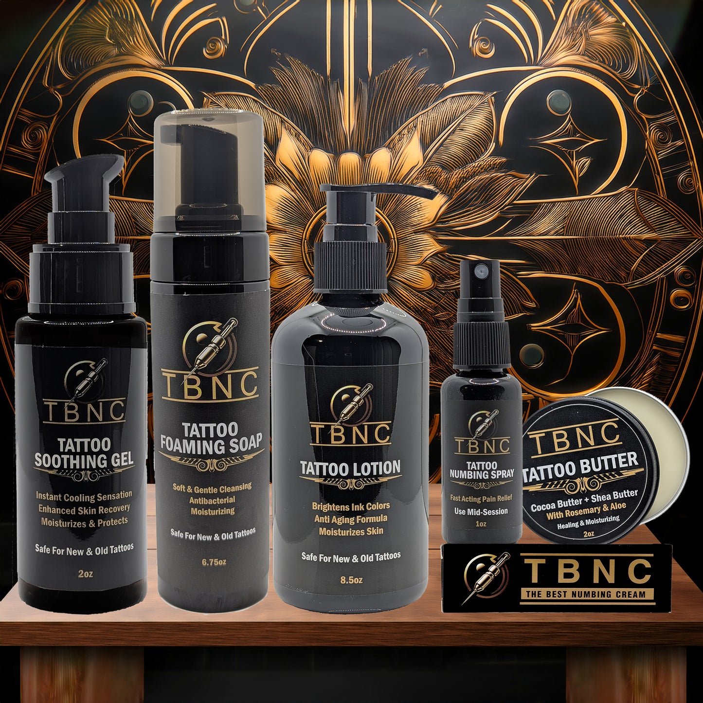 A display of the TBNC - The Best Numbing Cream Tattoo Numbing & Aftercare Bundle arranged in front of a decorative gold and black background.