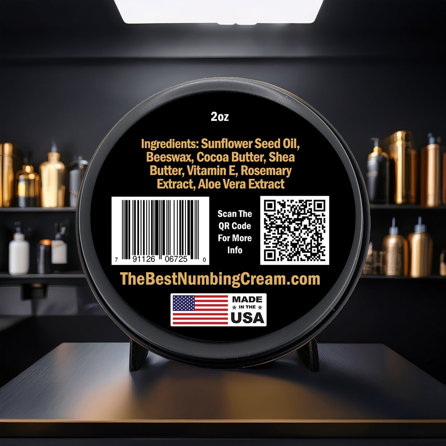 A round black TBNC - The Best Numbing Cream Tattoo Butter container displays ingredients like sunflower seed oil, beeswax, cocoa butter, shea butter, vitamin E, rosemary and aloe extracts on its label with a QR code, a US flag, and barcode visible.