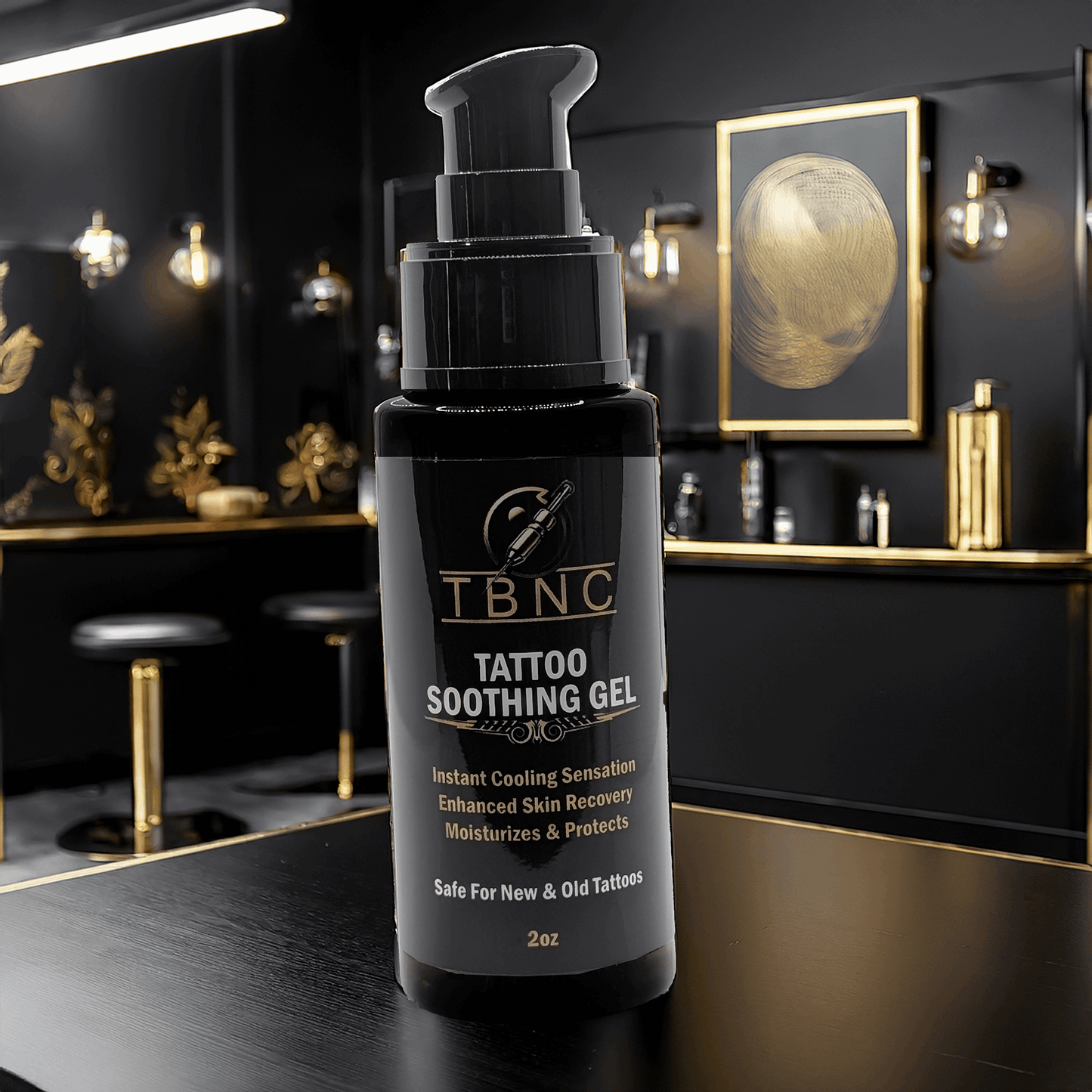 A bottle of TBNC Tattoo Soothing Gel is on a dark countertop in a dimly lit room with gold accents. The label emphasizes its cooling effect, enhanced tattoo vibrancy, and skin recovery benefits. Framed art and pendant lights add to the elegant ambiance.