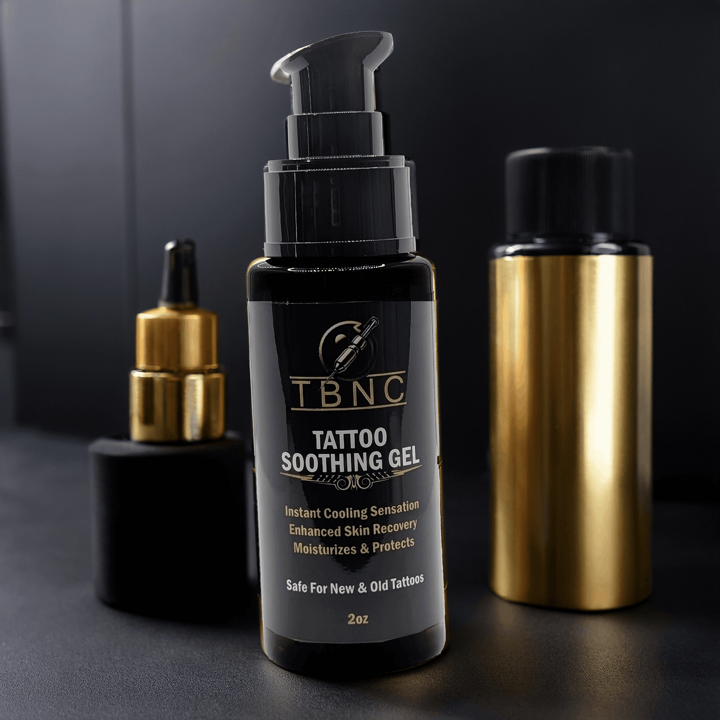 A black TBNC Tattoo Soothing Gel bottle rests on a dark surface, its pump poised to offer skin recovery. Behind it, gold and black bottles stand elegantly. The label highlights its tattoo vibrancy enhancement via cooling sensation and moisturizing care.