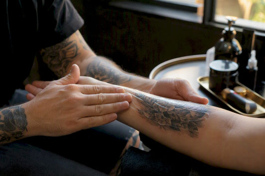 Hands applying balm on fresh tattooed skin