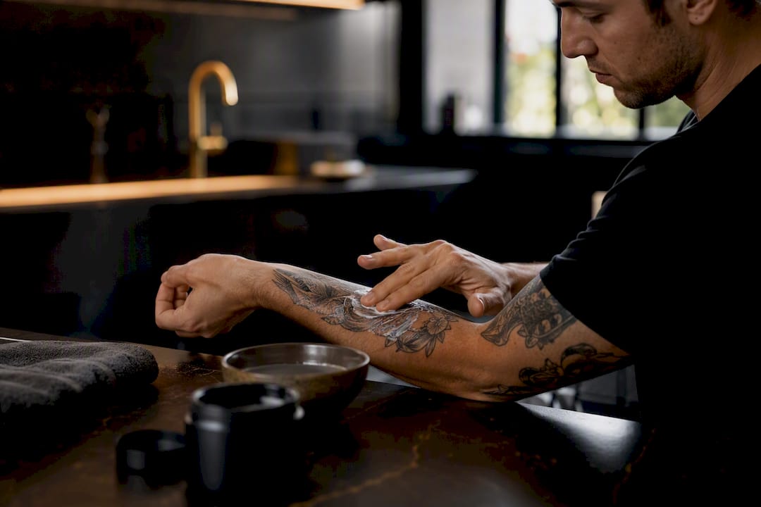 Hand applying balm on fresh tattooed forearm