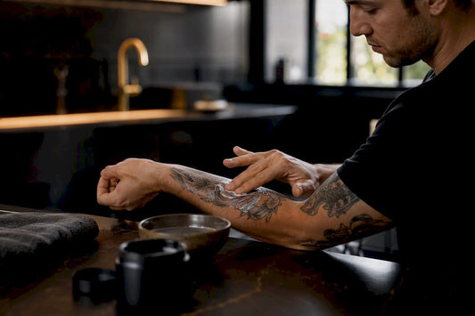 Hand applying balm on fresh tattooed forearm