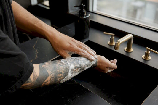 Hands washing fresh tattoo with soap lather