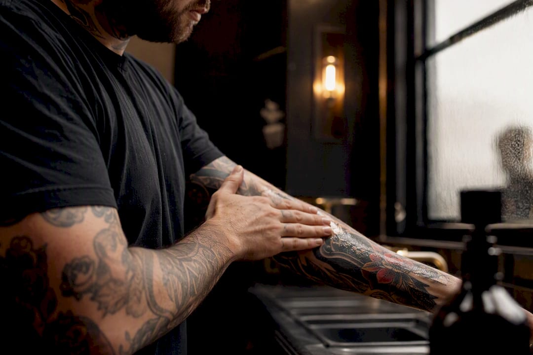 Applying lotion to vibrant tattooed arm