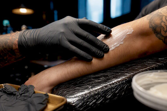 Artist applying topical numbing cream before tattooing
