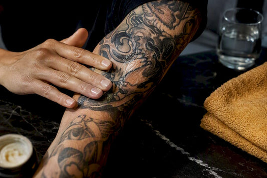 Hands applying balm to healing tattoo