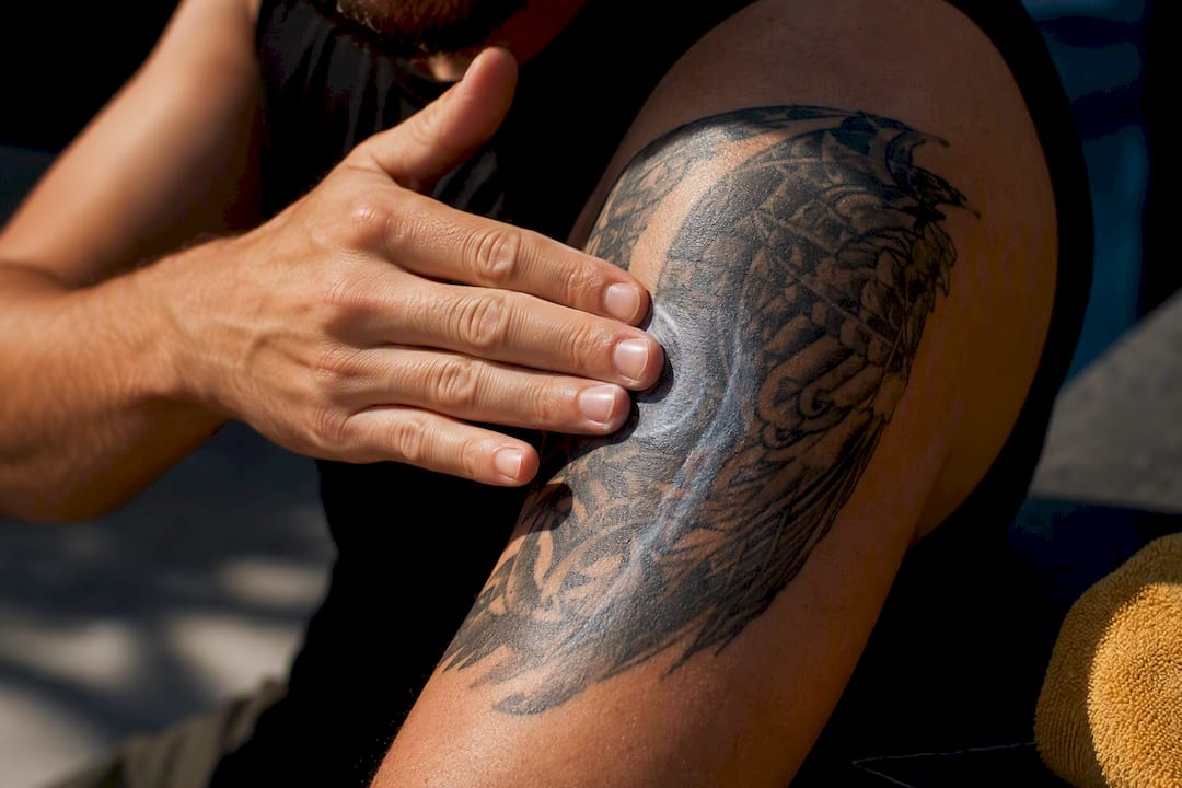 Person patting sunscreen onto healed tattoo