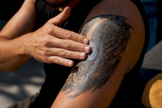 Person patting sunscreen onto healed tattoo