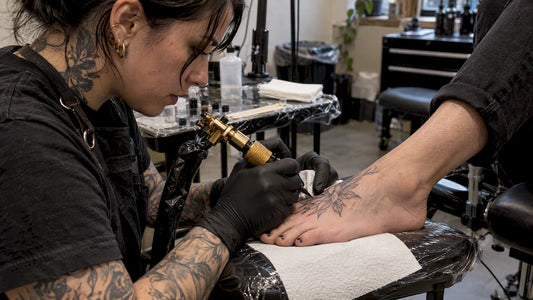 Artist tattooing the top of a foot