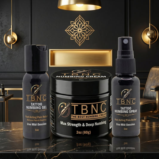 The TBNC Max Tattoo Numbing Bundle—gel, cream, spray—shines on a luxe surface in a bold, high-end black and gold display.