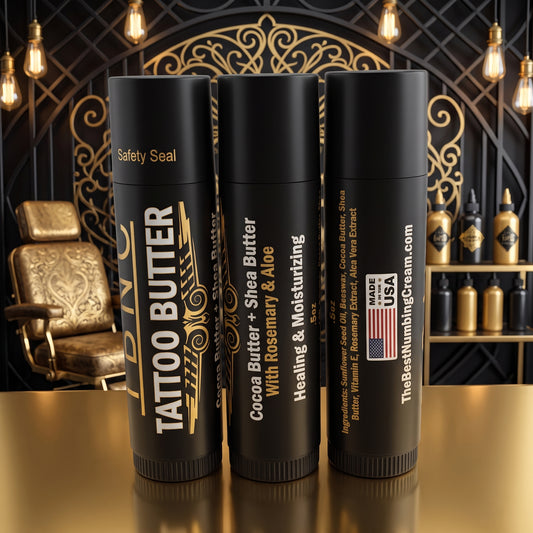 Three Tattoo Butter Travel Sticks (3pack) by The Best Numbing Cream on a gold counter, shown as premium tattoo aftercare essentials.
