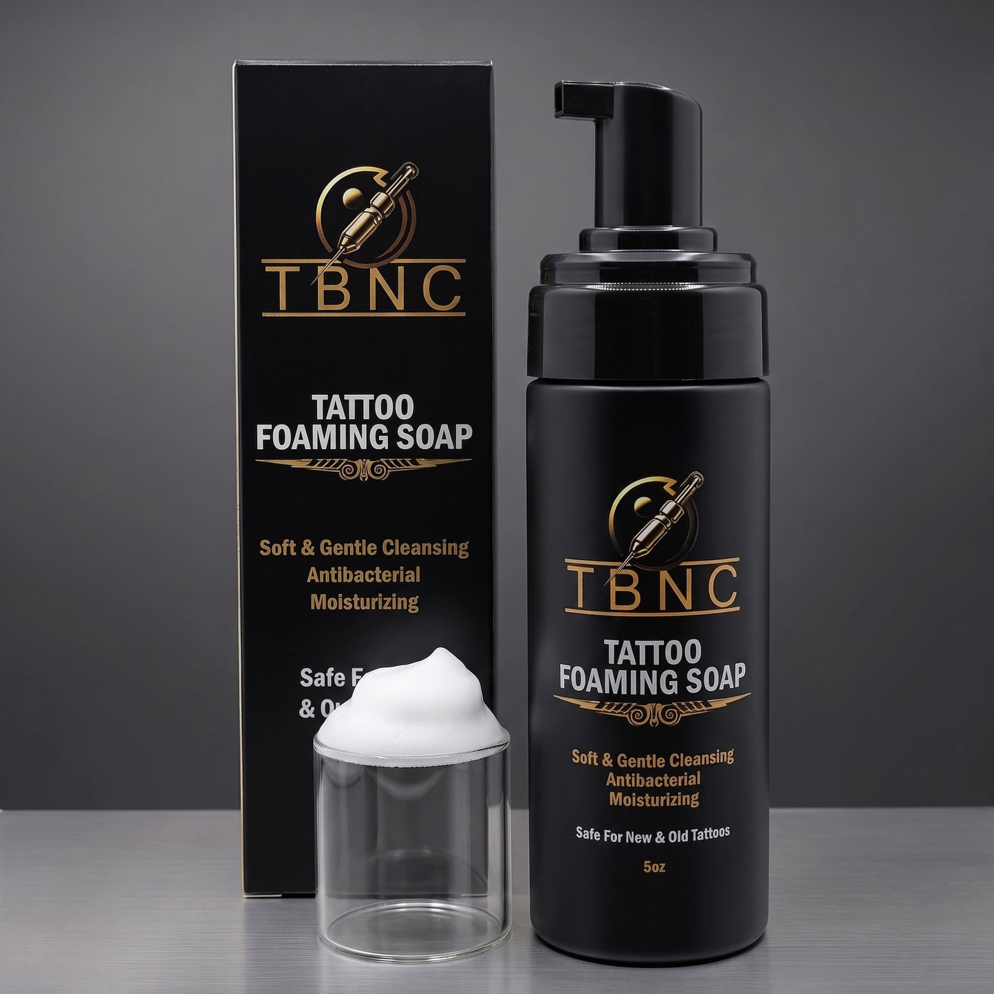 Premium TBNC Tattoo Foaming Soap, bottle and box, with luxe black-gold packaging and white foam, showcased on a sleek gray surface.