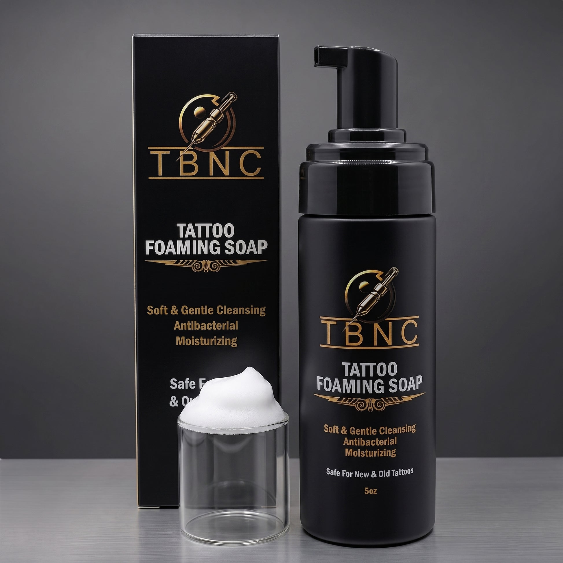 Premium TBNC Tattoo Foaming Soap, bottle and box, with luxe black-gold packaging and white foam, showcased on a sleek gray surface.