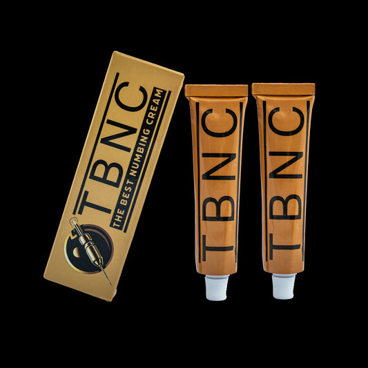 Two orange TBNC Tattoo Numbing Cream XL tubes with white caps are shown beside a TBNC - The Best Numbing Cream box featuring a needle graphic, all set against a sleek black background. This is the 2 pack version.