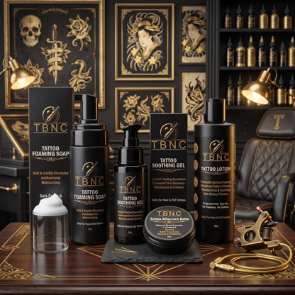 A premium Tattoo Aftercare Bundle, similar to those offered by top-selling tattoo aftercare brands, is expertly arranged on a wooden desk. The set includes professional-grade essentials—soap, gel, lotion, and balm—showcased alongside tattoo equipment with striking gold-accented art and books in the background. The inviting and stylish display highlights the high quality and trusted reputation of these aftercare products.