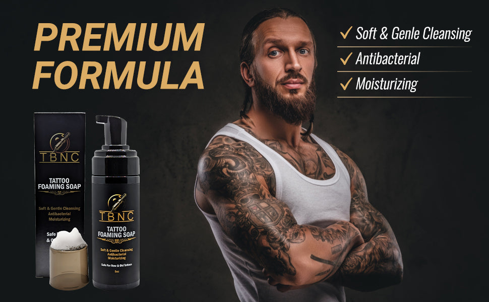 A bearded, tattooed man stands confidently with arms crossed beside TBNC - The Best Numbing Cream Tattoo Foaming Soap. Text highlights: "Premium Formula," "Soft & Gentle Cleansing," "Antibacterial tattoo soap," and "Moisturizing.