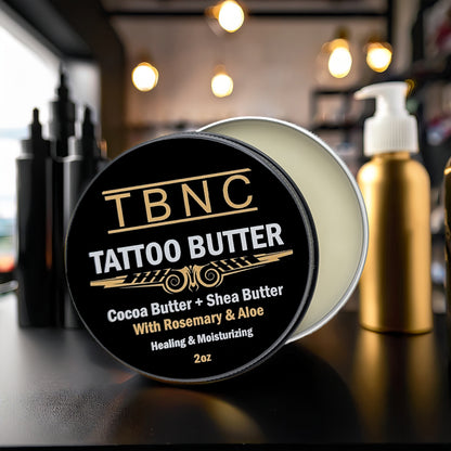 A premium tin of TBNC Tattoo Butter, lid open to reveal rich cream. Elite ingredients list on label. Sleek, blurred backdrop.