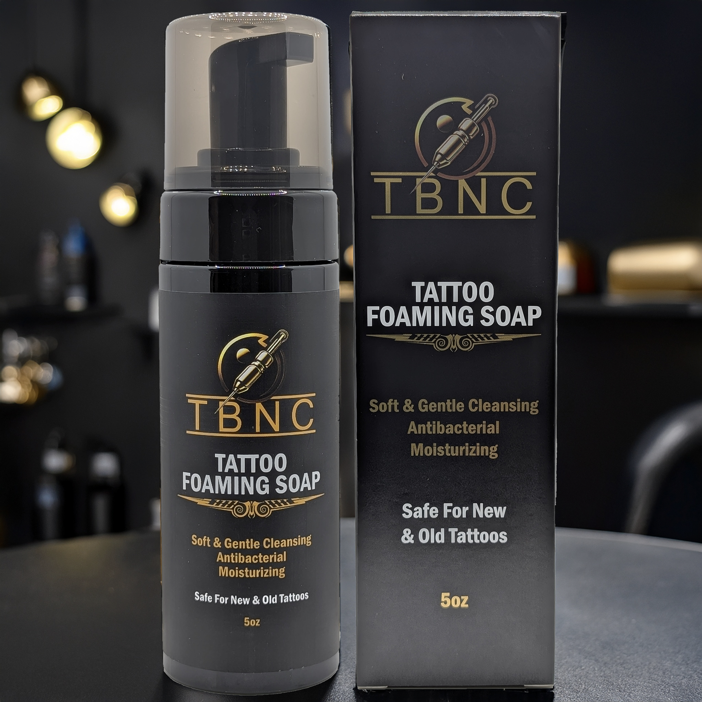 A 5oz bottle and box of TBNC - The Best Numbing Cream Tattoo Foaming Soap, a gentle, antibacterial, and moisturizing cleanser safe for caring for new or old tattoos. Displayed on a dark background.