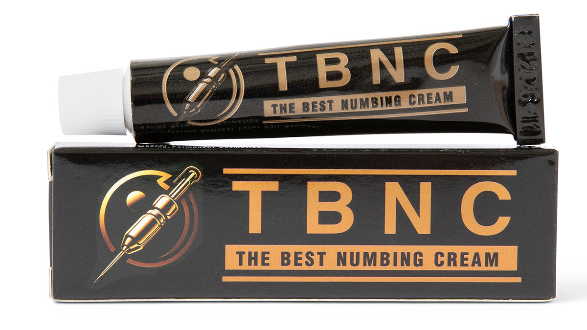 Image of a black tube of "The Best Numbing Cream - TBNC," resting on its matching black and gold packaging box. Ideal for pain-free tattoos, the box and tube feature a graphic of a needle with a drop at the tip. This product is part of the "The Best Numbing Cream - TBNC - 4 Pack.